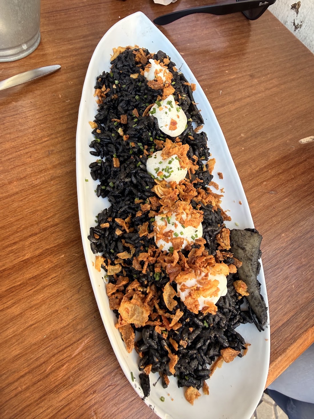 Arroz negro con alioli y cebolla crujiente en fuente alargada