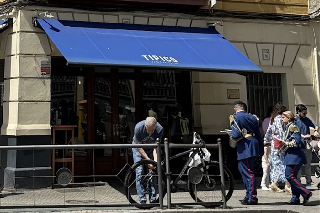 Entrada de Bar Típico bajo su toldo azul con el nombre del bar, en Triana