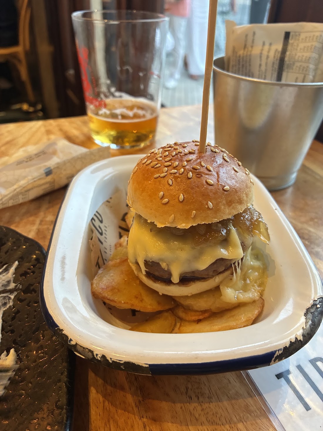 Hamburguesa con queso y patatas junto a una cerveza