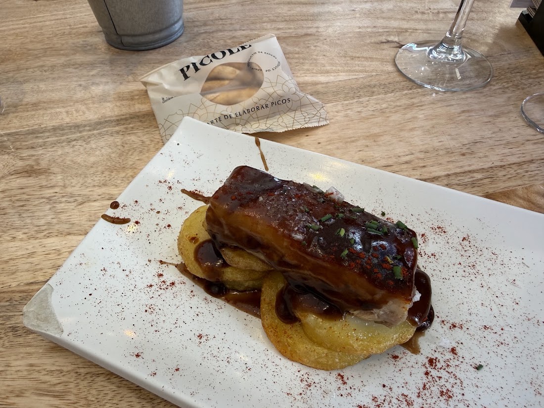 Tapa de carne glaseada sobre patata, en plato blanco